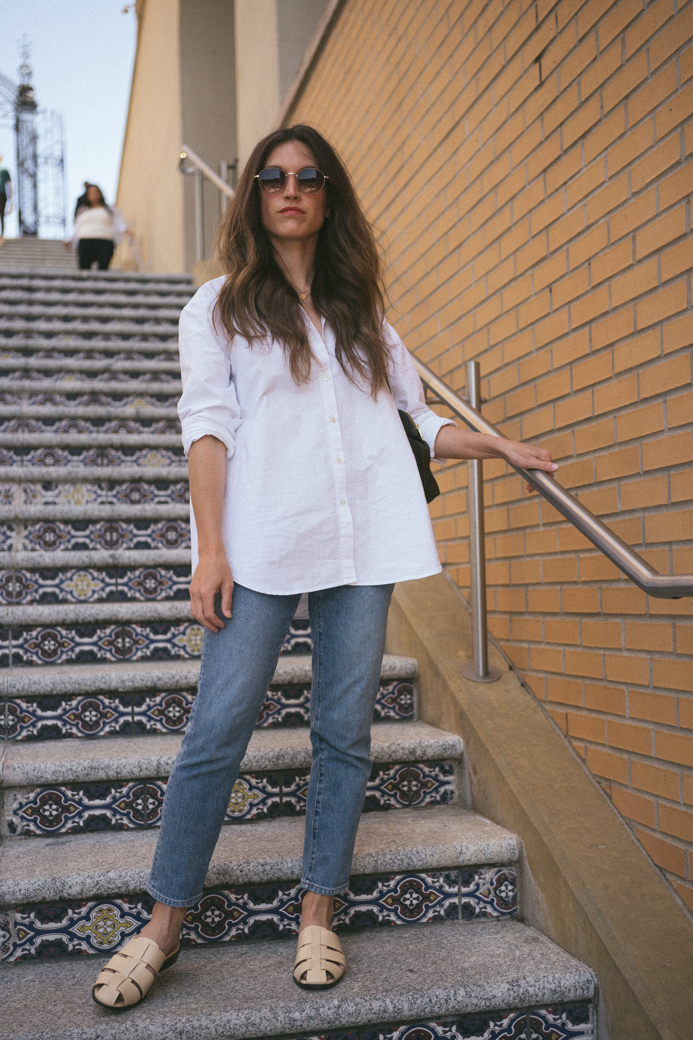 spring outfit with an oversized white button down, slim cut medium wash denim, and cream colored fisherman mules