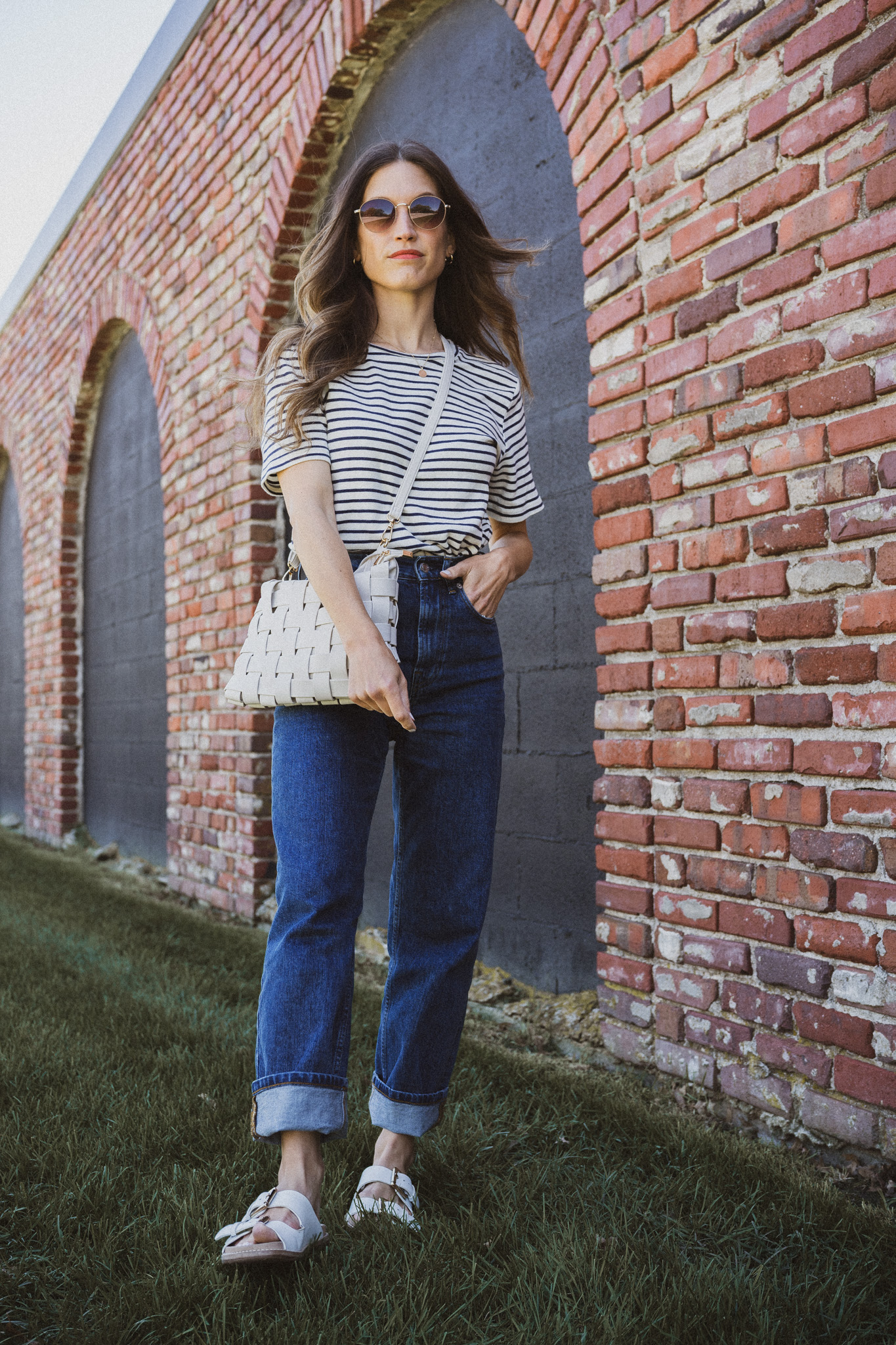 spring outfit idea with a white and navy striped tee, dark wash straight denim cuffed, and white sandals