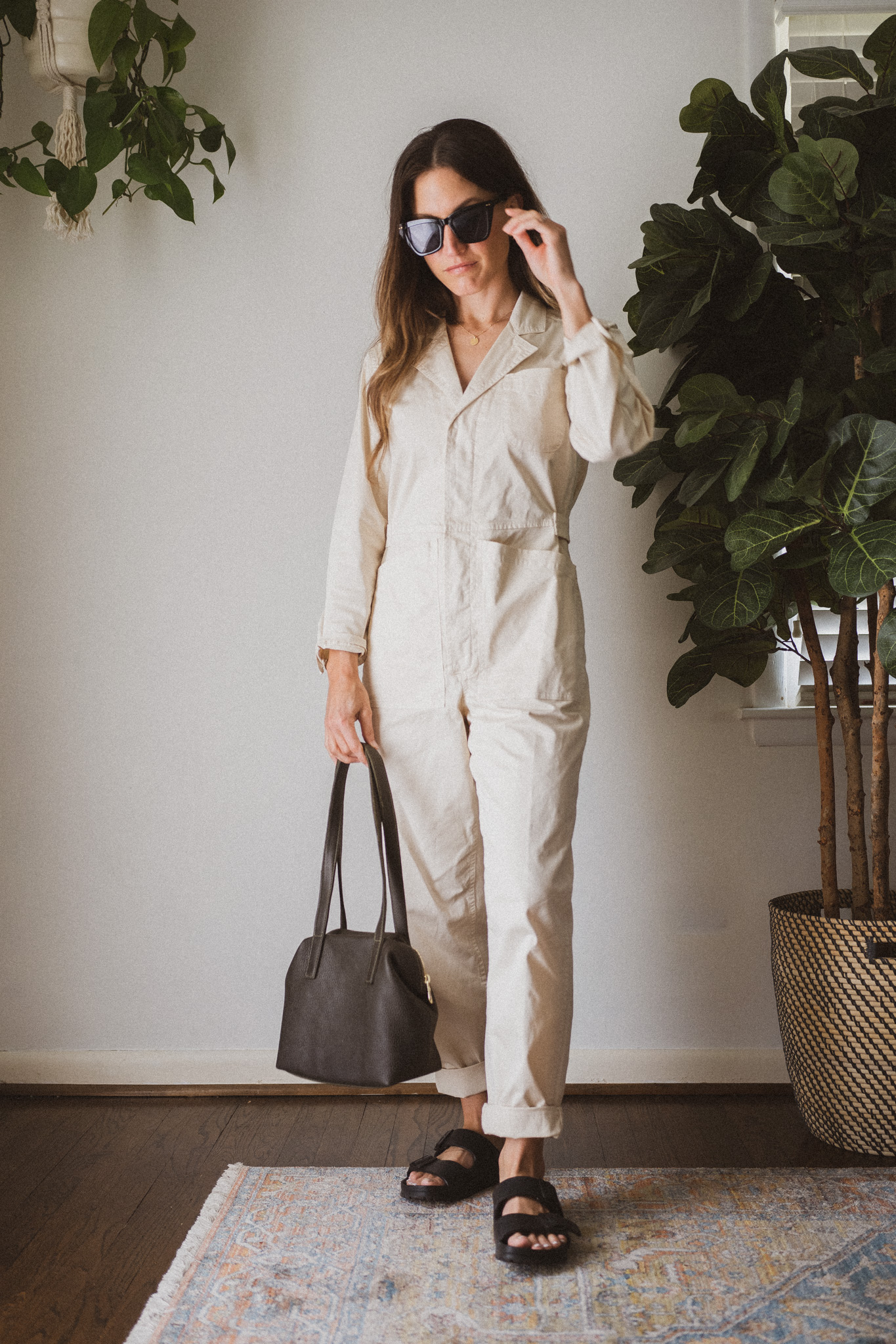 casual spring look with an ivory utility jumpsuit, green leather bag, and black birkenstock sandals