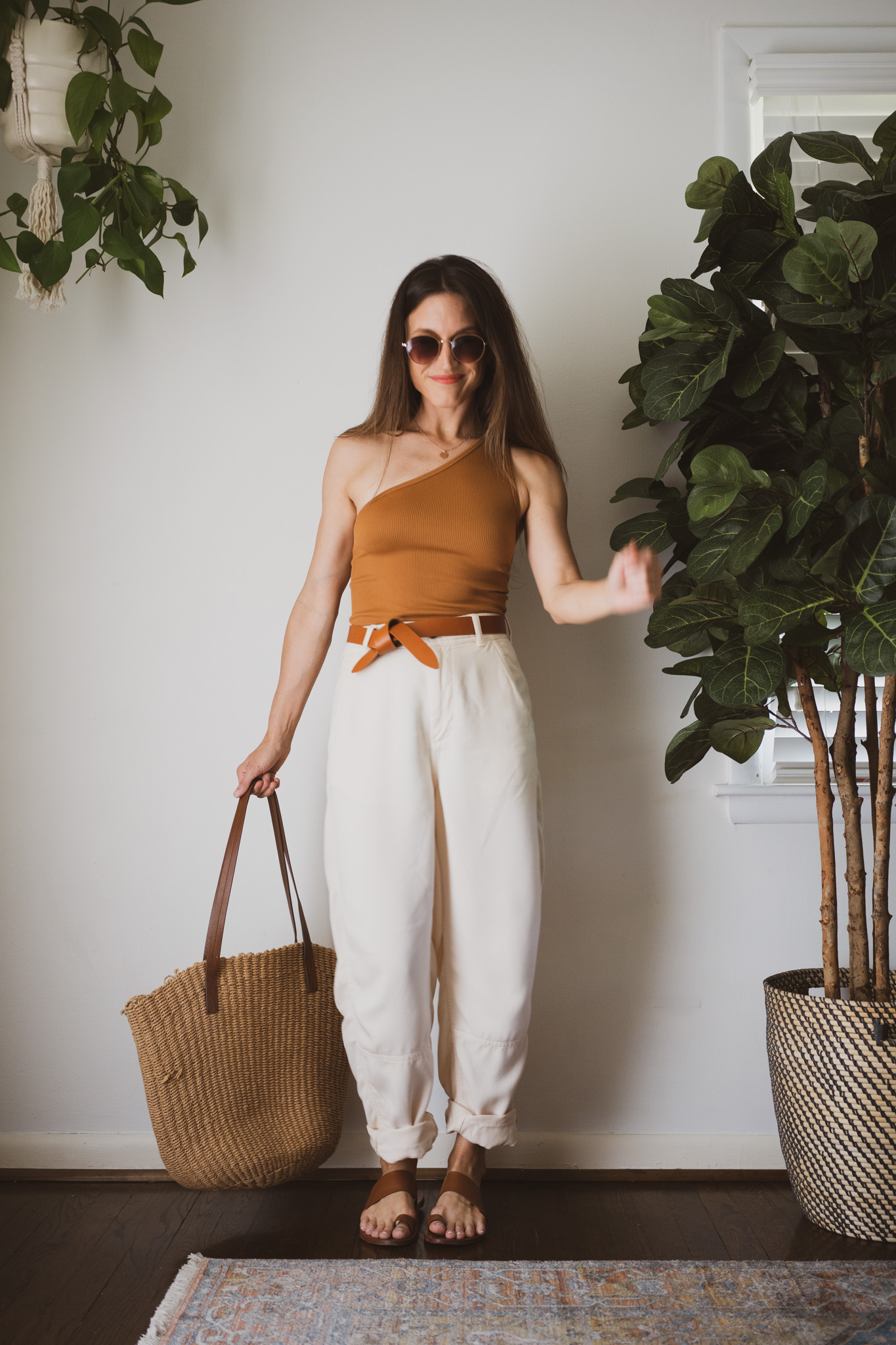 spring look for 2023 with a brown one strap ribbed tank, tapered chino pants, and brown leather sandals