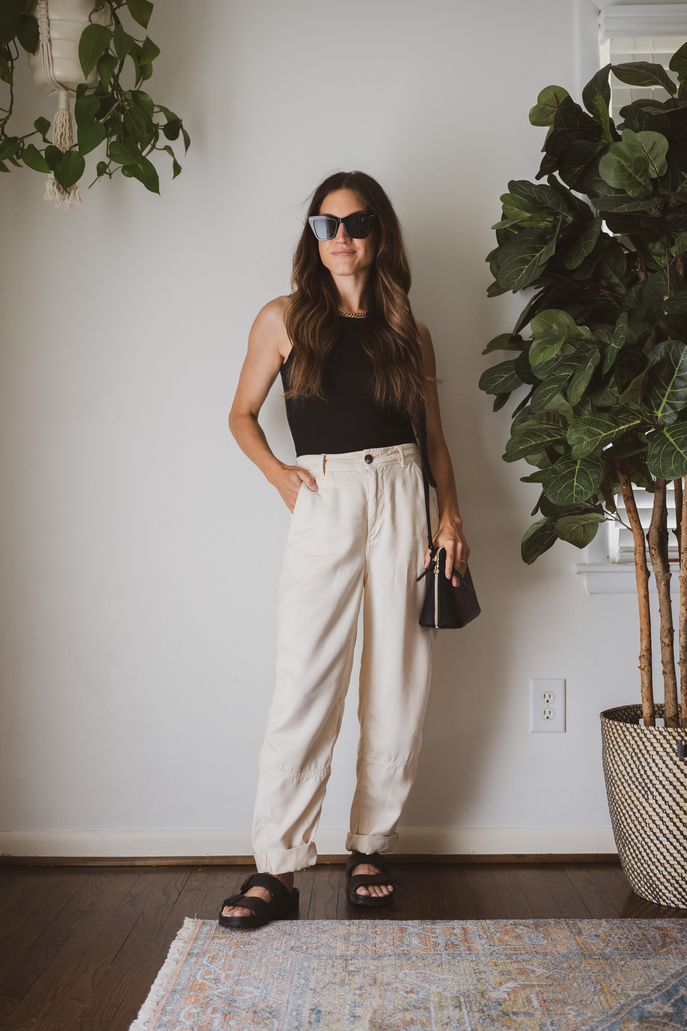 minimalist outfit with a black tank, tapered chinos, and black sandals with a black crossbody bag