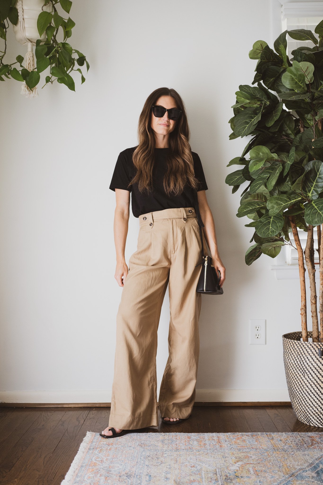minimalist outfit with a black tee, wide leg tan trousers, black sandals, and a black crossbody bag
