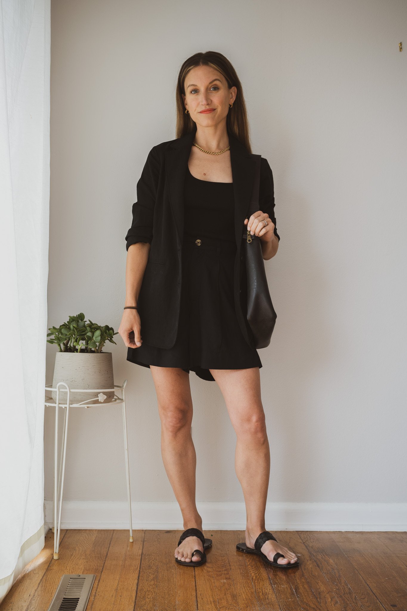 minimal outfit with a black tank, black relaxed fit blazer, black trouser shorts, and black sandals