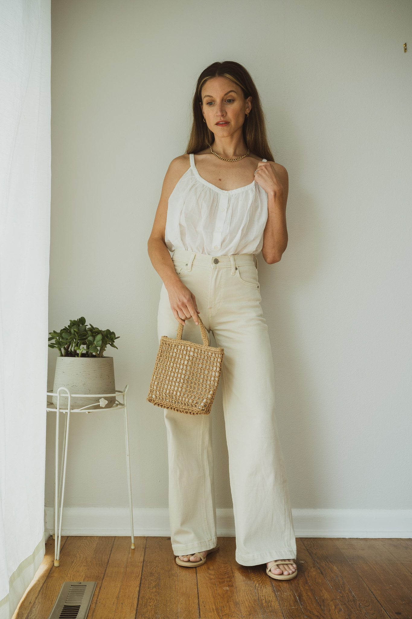 minimal outfit ideas with a white blouse, ecru wide leg jeans, and nude sandals with a straw handbag