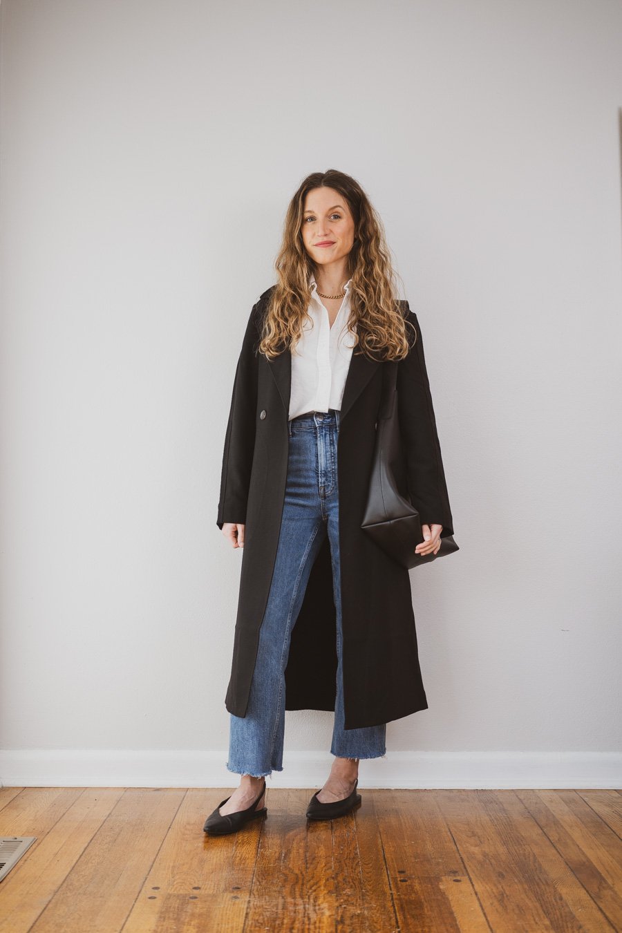 outfit with a black trench coat, a white button down, medium wash cropped jeans, and black slingback flats