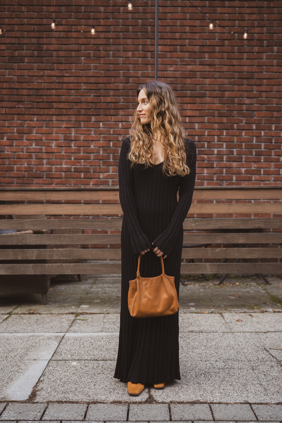 ashley wearing the black dissh reign dress with brown boots and a brown handbag