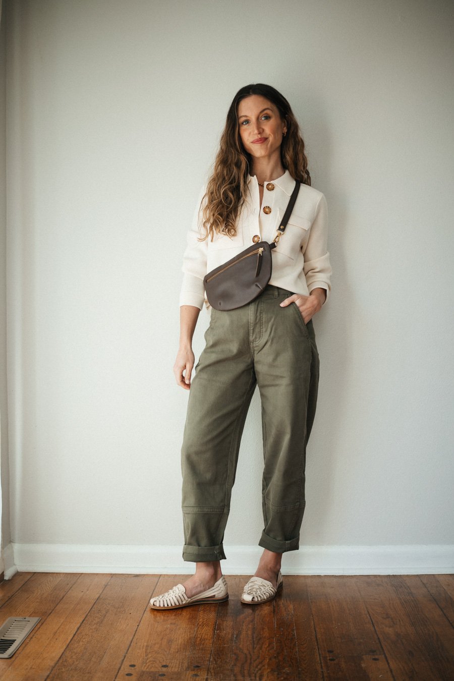 outfit with green pants, ecru cardigan, huarache sandals, and a brown sling bag