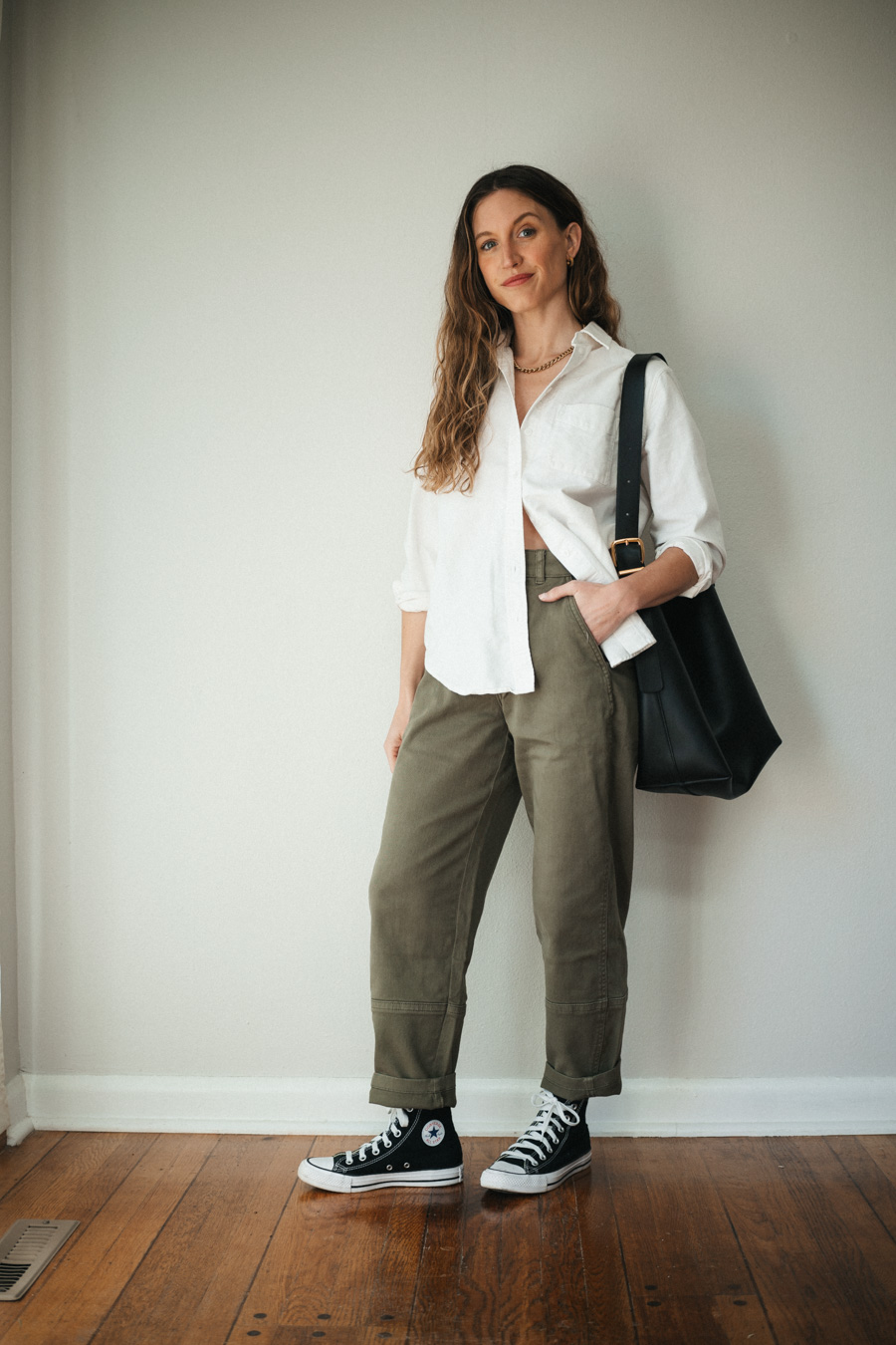 outfit with green cargo pants, a white button down, black high top Converse, and a black tote bag
