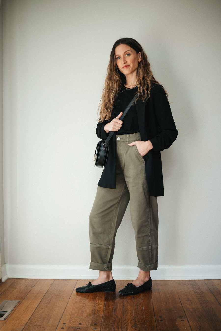 outfit with green pants, black tee, black blazer, black woven ballet flats, and a black crossbody bag