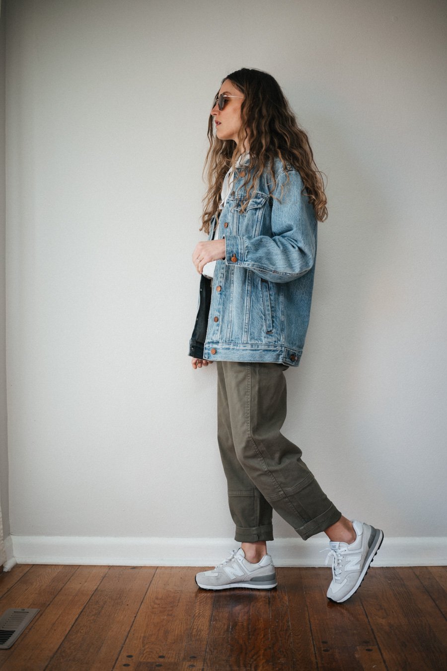 an outfit with green cargo pants, gray hoodie, oversized denim jacket, and New Balance sneakers