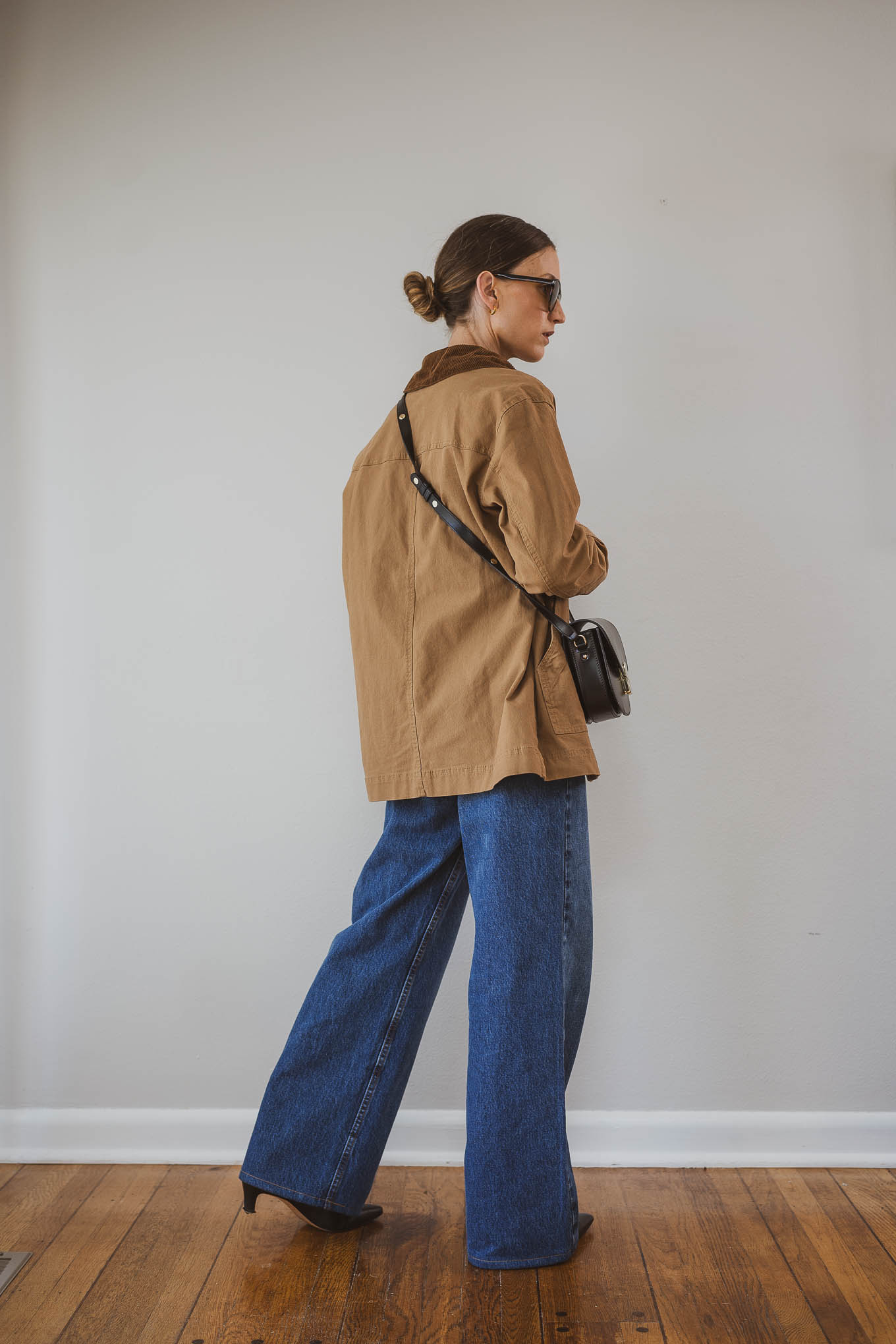 fall capsule wardrobe outfit with a black and white striped top, barn jacket, medium wash wide leg jeans, and black boots