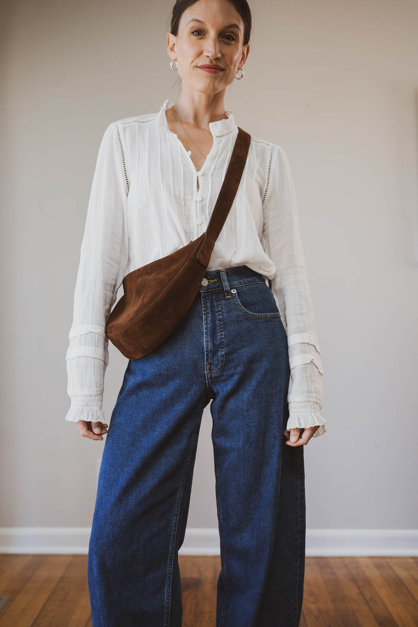 fall capsule wardrobe outfit with a white blouse, barrel jeans, tan woven ballet flats, and a brown suede crossbody bag