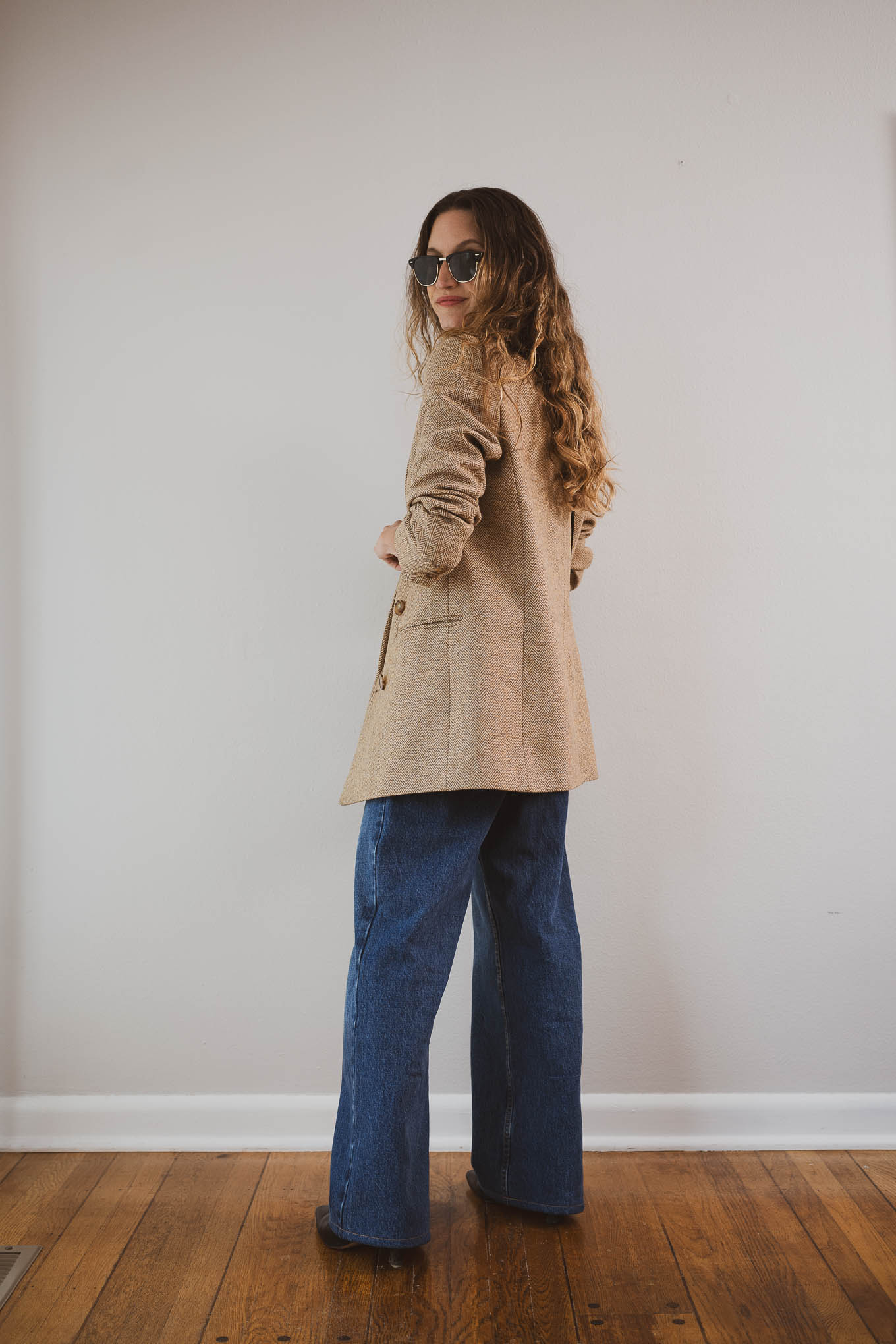 fall outfit idea with a black tee, tan herringbone blazer, wide leg jeans, and black boots