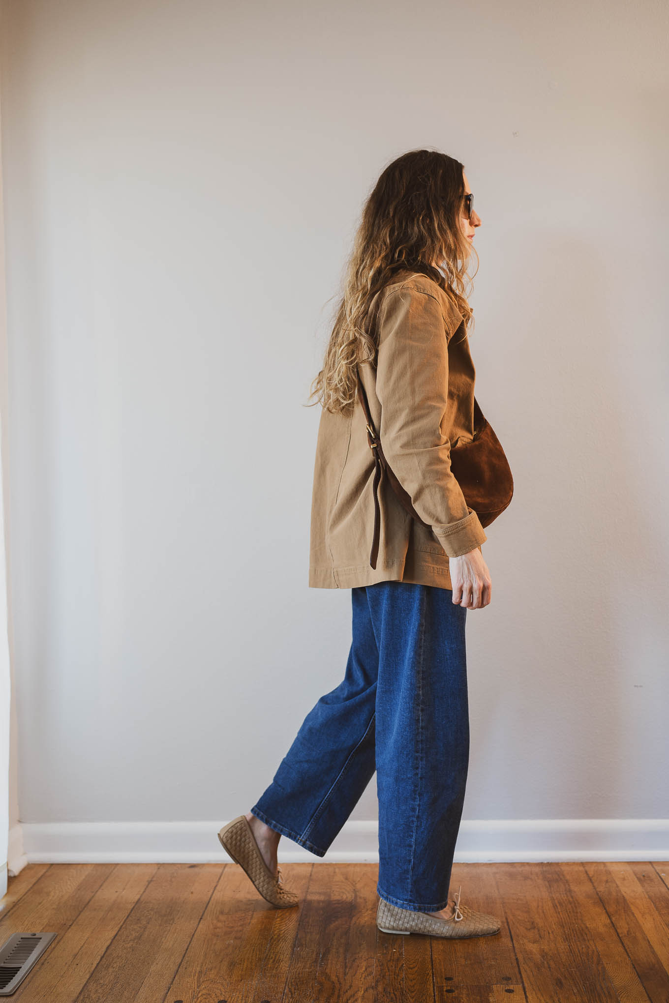 fall capsule wardrobe outfit with a beige fitted sweater, barn jacket, barrel jeans, tan woven ballet flats and a brown suede crossbody bag