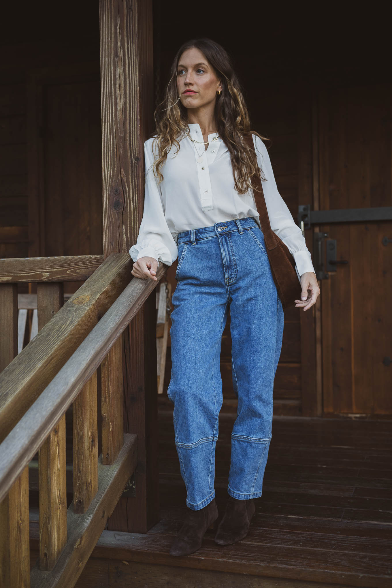western inspired outfit with a henley silk top, barrel style utility jeans, suede boots, and a suede crossbody bag