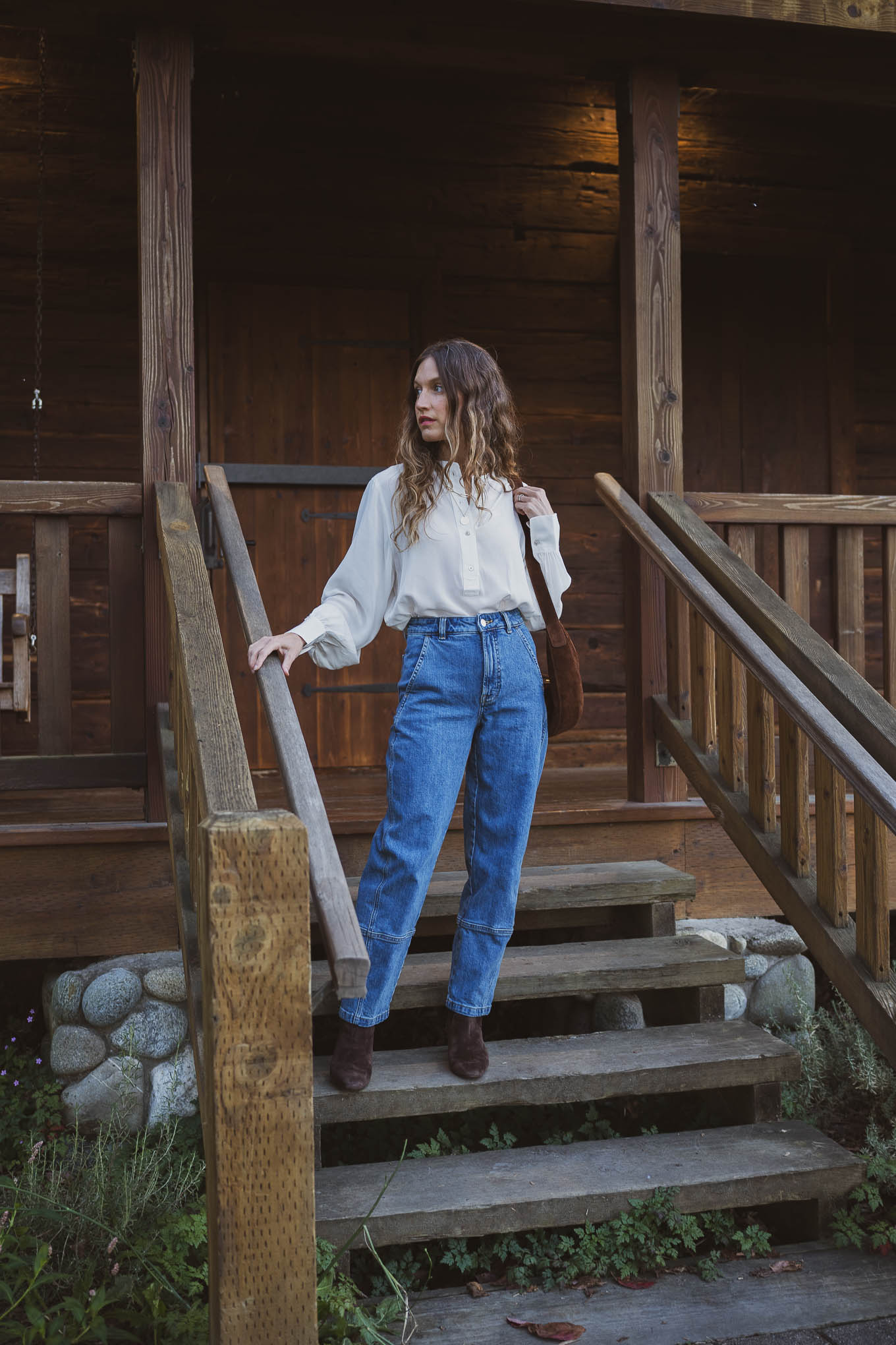 western inspired outfit with a henley silk top, barrel style utility jeans, suede boots, and a suede crossbody bag
