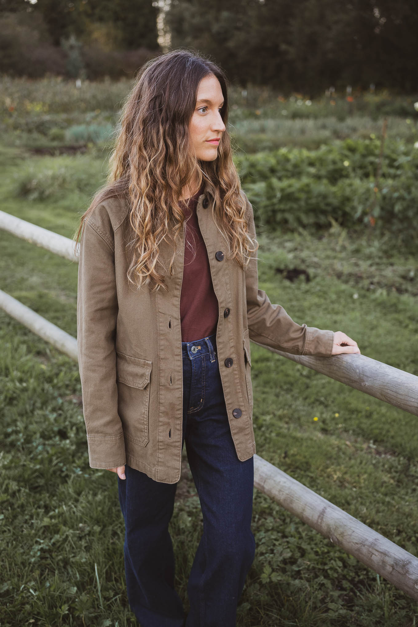western inspired outfit with a green barn jacket, brown crewneck tee, dark wash jeans, and brown suede boots
