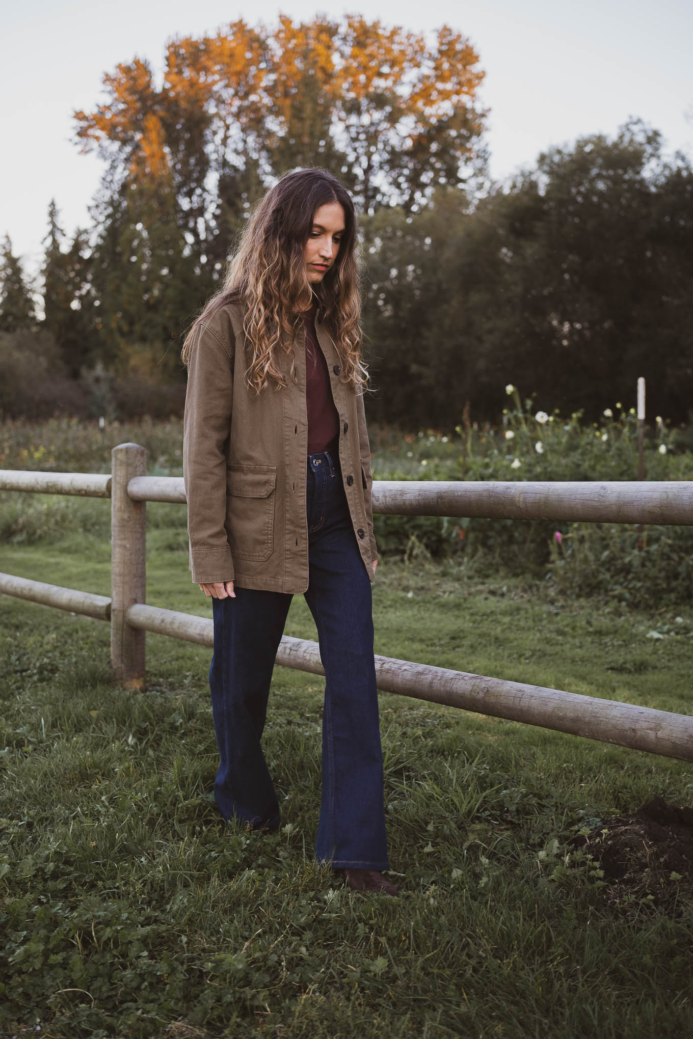 western inspired outfit with a green barn jacket, brown crewneck tee, dark wash jeans, and brown suede boots