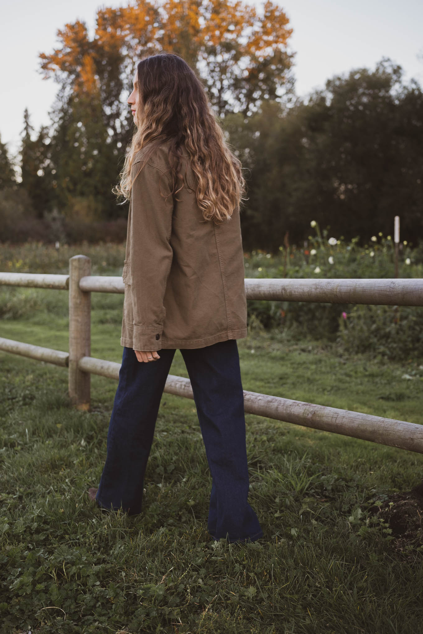 western inspired outfit with a green barn jacket, brown crewneck tee, dark wash jeans, and brown suede boots