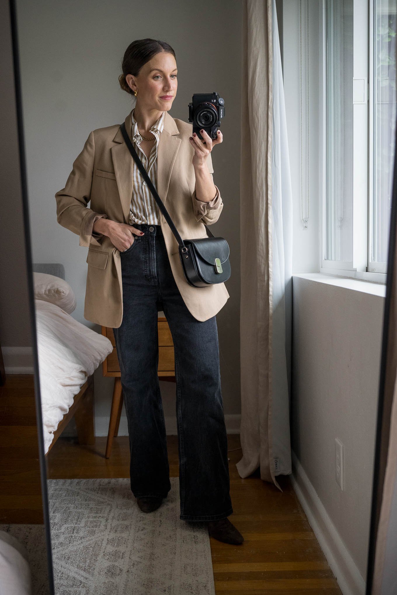 casual chic winter outfit with a camel and cream striped button down, camel blazer, black full length jeans, and brown heeled boots with a black leather crossbody bag