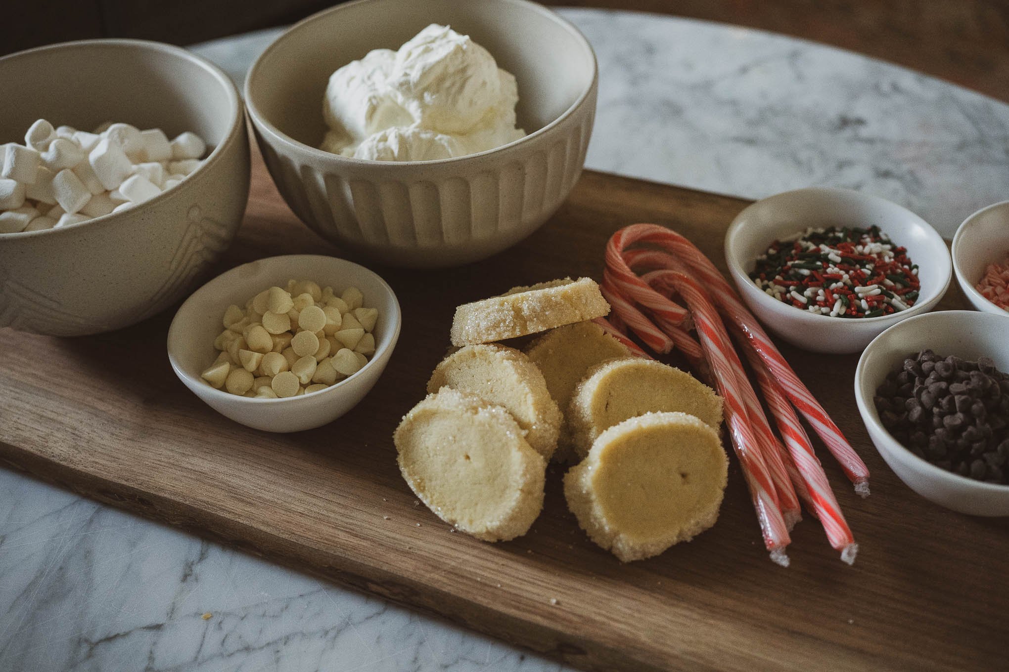 how to make an easy hot chocolate bar; hot chocolate bar toppings including candy canes, chocolate chips, whipped cream, marshmallows, and sprinkles
