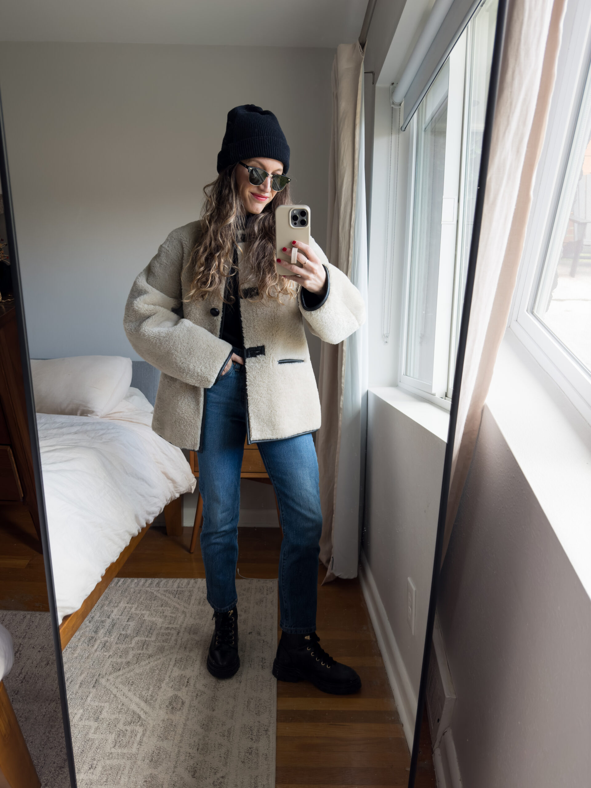 casual chic winter outfit with a black turtleneck, faux fur coat, slim cut dark wash denim, black combat boots, and a black beanie