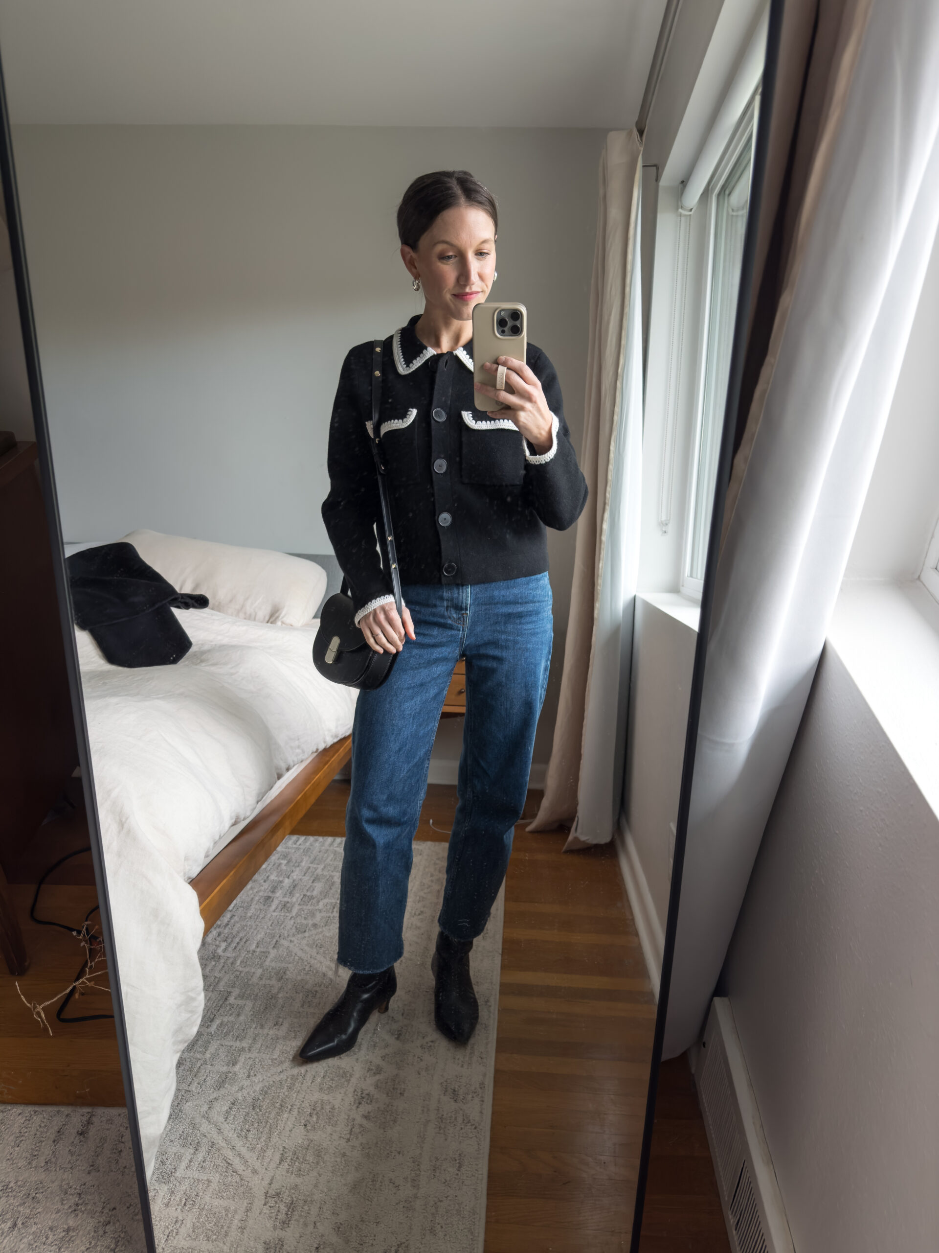 casual chic winter outfit with a black lady jacket, dark wash straight leg jeans, black heeled boots, and a black crossbody bag