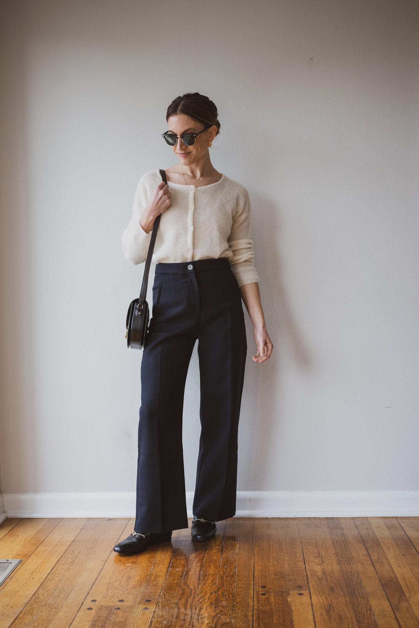 how to style loafers with an ecru cardigan sweater, navy cropped trousers, and black loafers