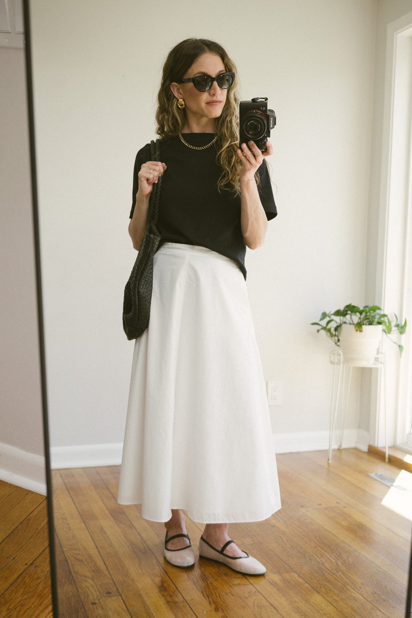 white poplin skirt outfit with a black tee, white skirt, black sandals, and a black woven bag