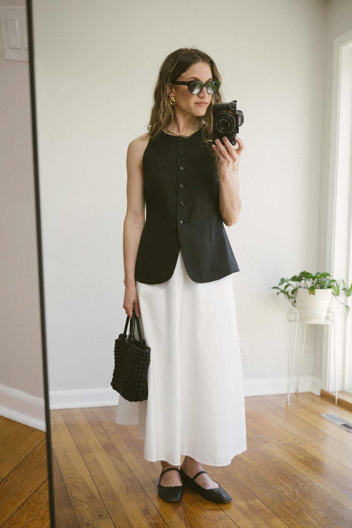 white poplin skirt outfit with a black waistcoat, white skirt, black mary jane ballet flats, and a black woven bag