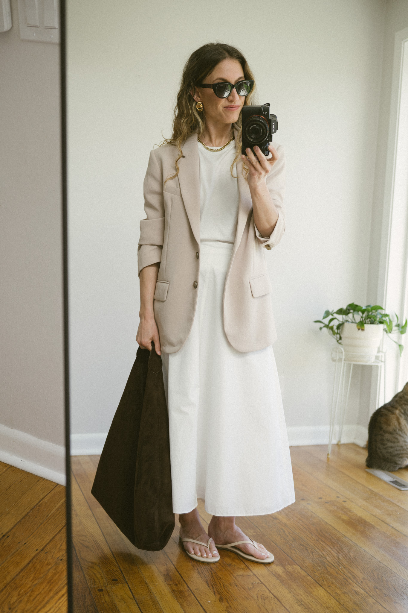 white poplin skirt outfit with a white tee, beige blazer, white skirt, and flip flops