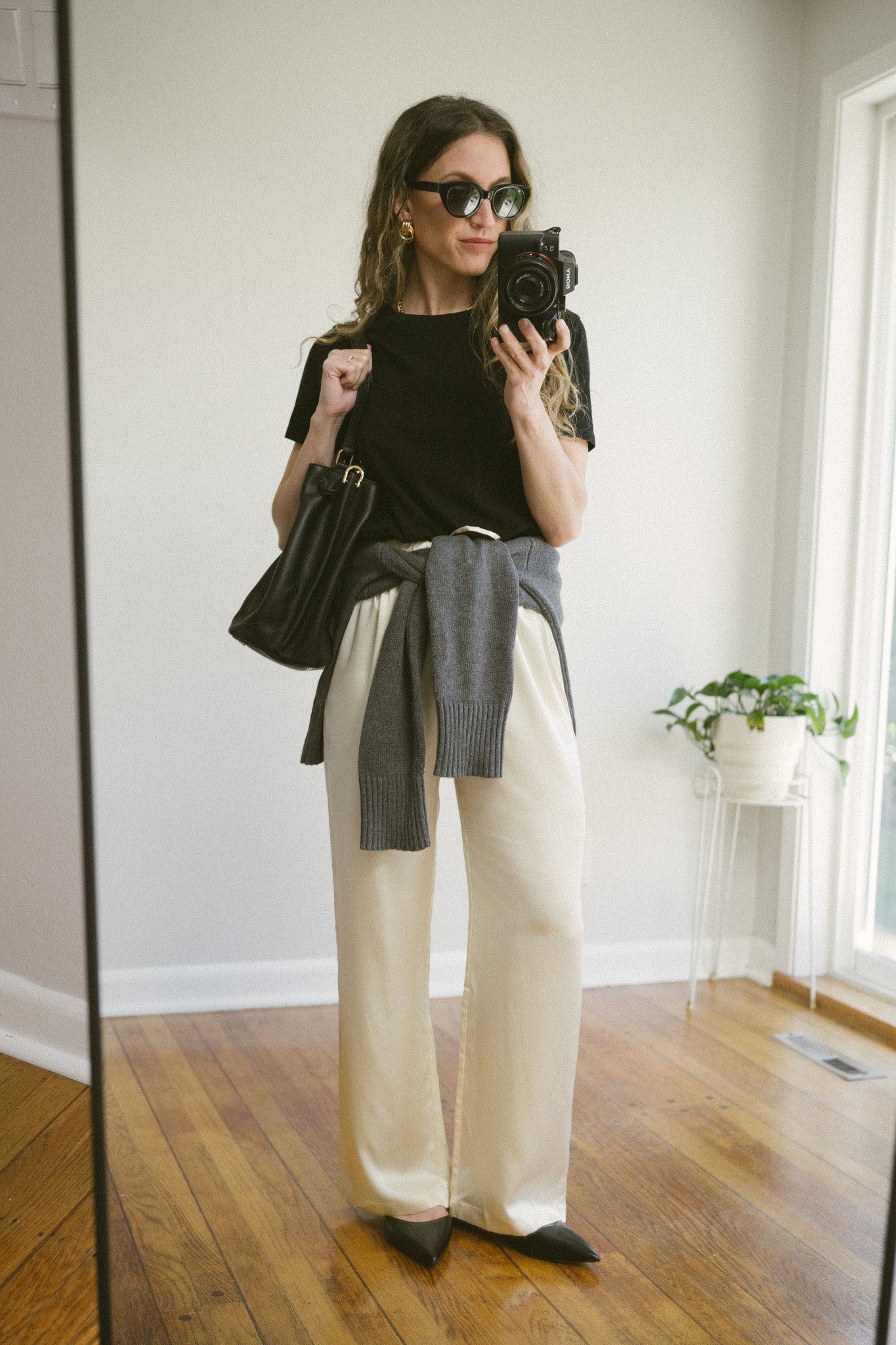 silk pants outfits with a black tee, gray sweater tied at the waist, black slingback flats, and a black leather shoulder bag