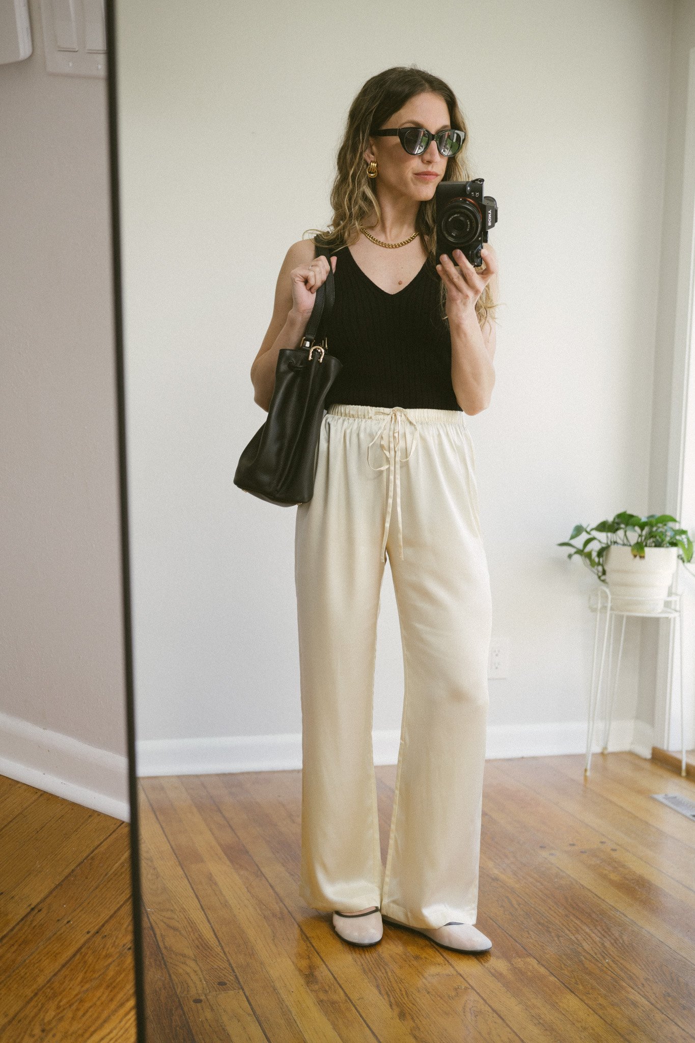 silk pants outfit with a black sweater tank, cream silk pants, and mesh ballet flats
