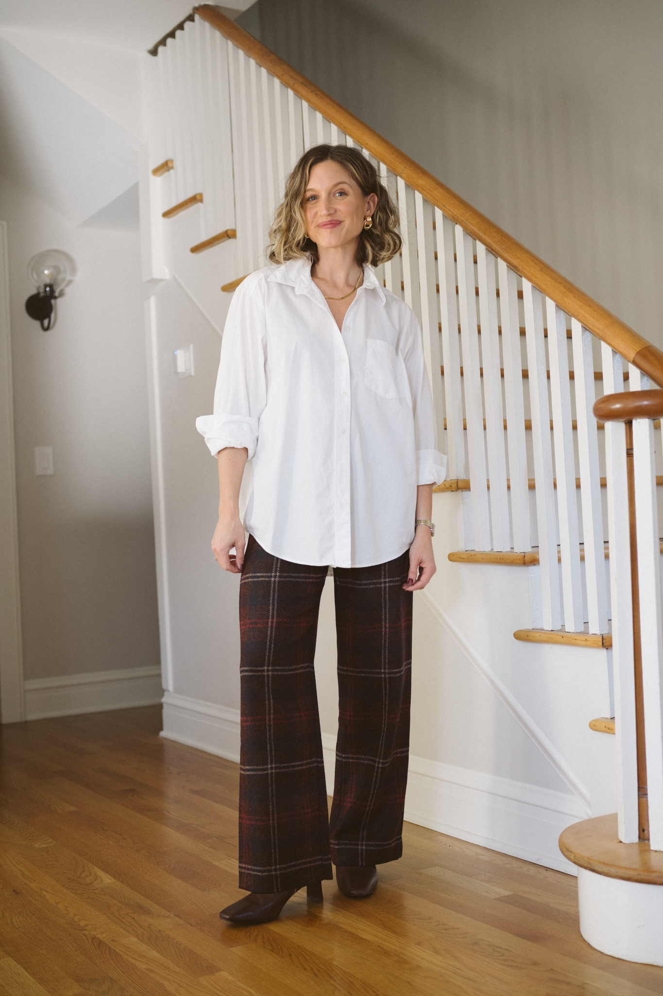 thanksgiving outfit with a white button down, tartan trousers, and brown boots