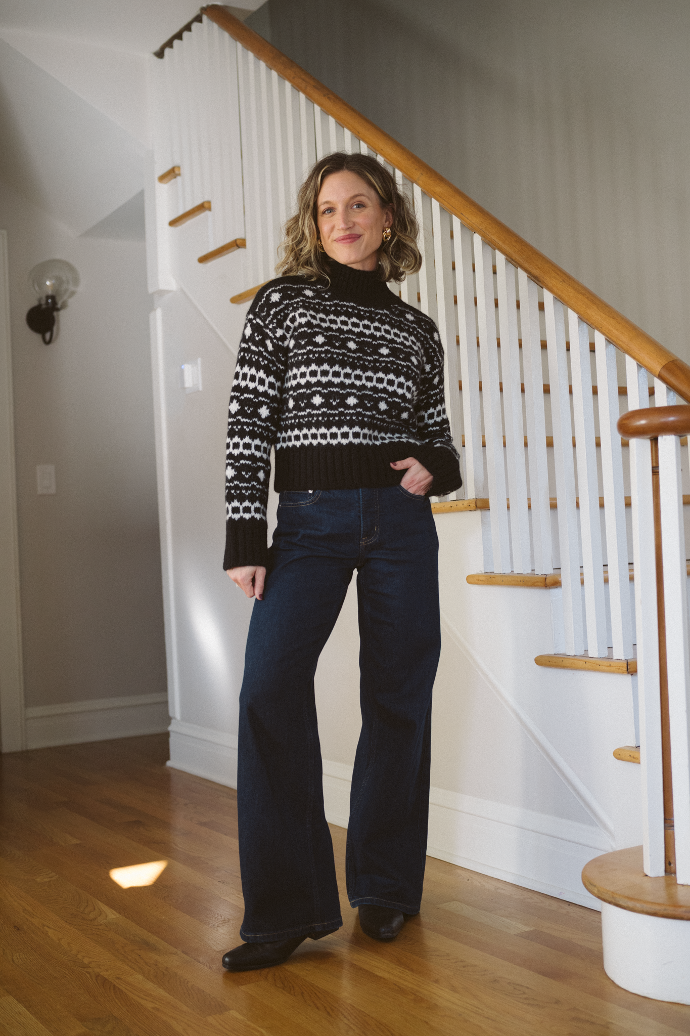thanksgiving outfit with a black fair isle sweater, dark wash jeans, and black boots
